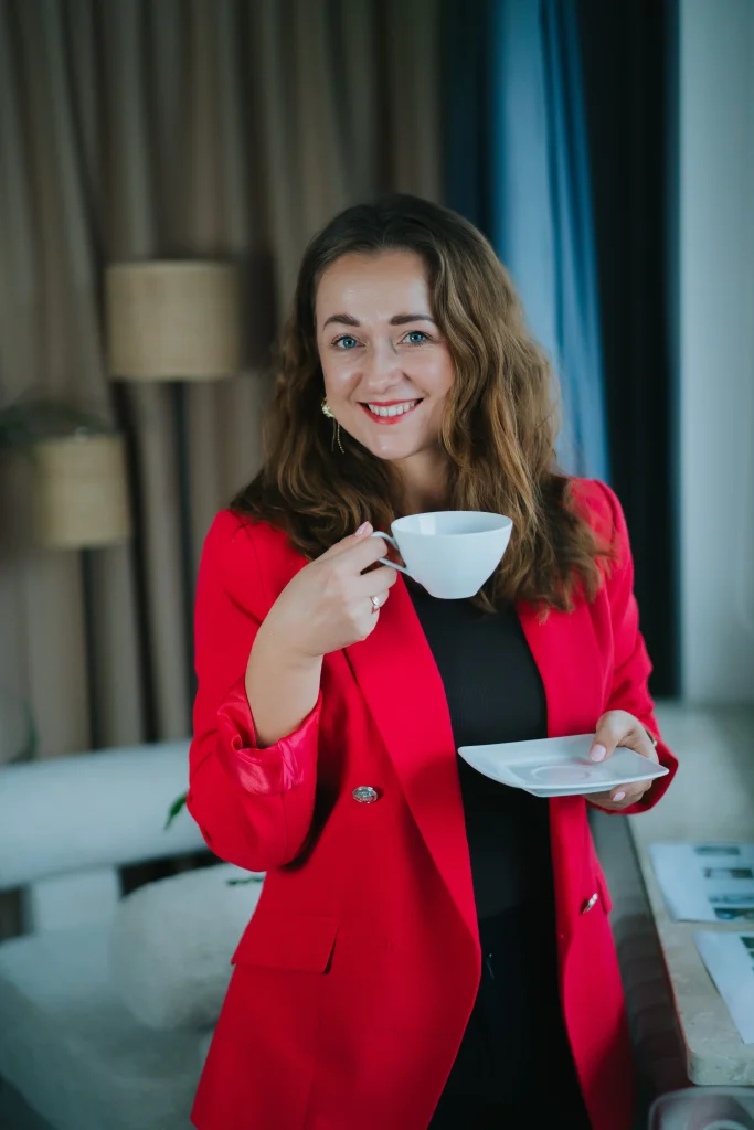 Kobieta w czerwonym żakiecie z filiżanką, biuro agencji marketingu internetowego.