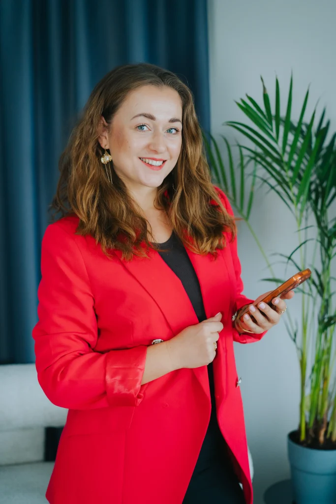 Social SEO 2 Agencja marketingowa Ambitna Marka, kobieta w czerwonej marynarce z telefonem, pozycjonowanie i social media.