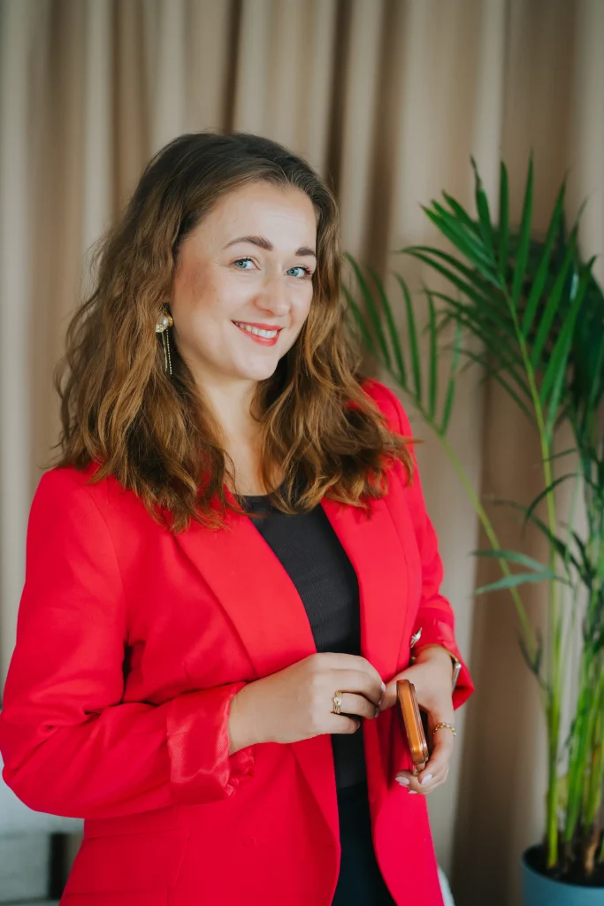 Specjalistka ds. marketingu internetowego w czerwonej marynarce w biurze agencji Ambitna Marka.