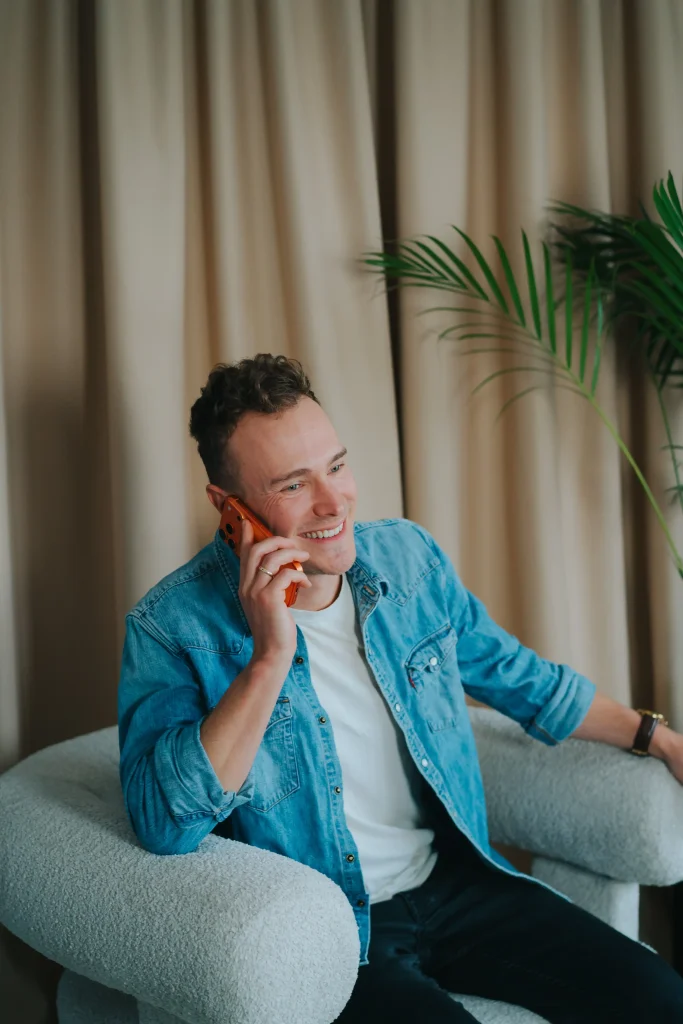 Mężczyzna w dżinsowej koszuli rozmawiający przez telefon w biurze agencji marketingowej.